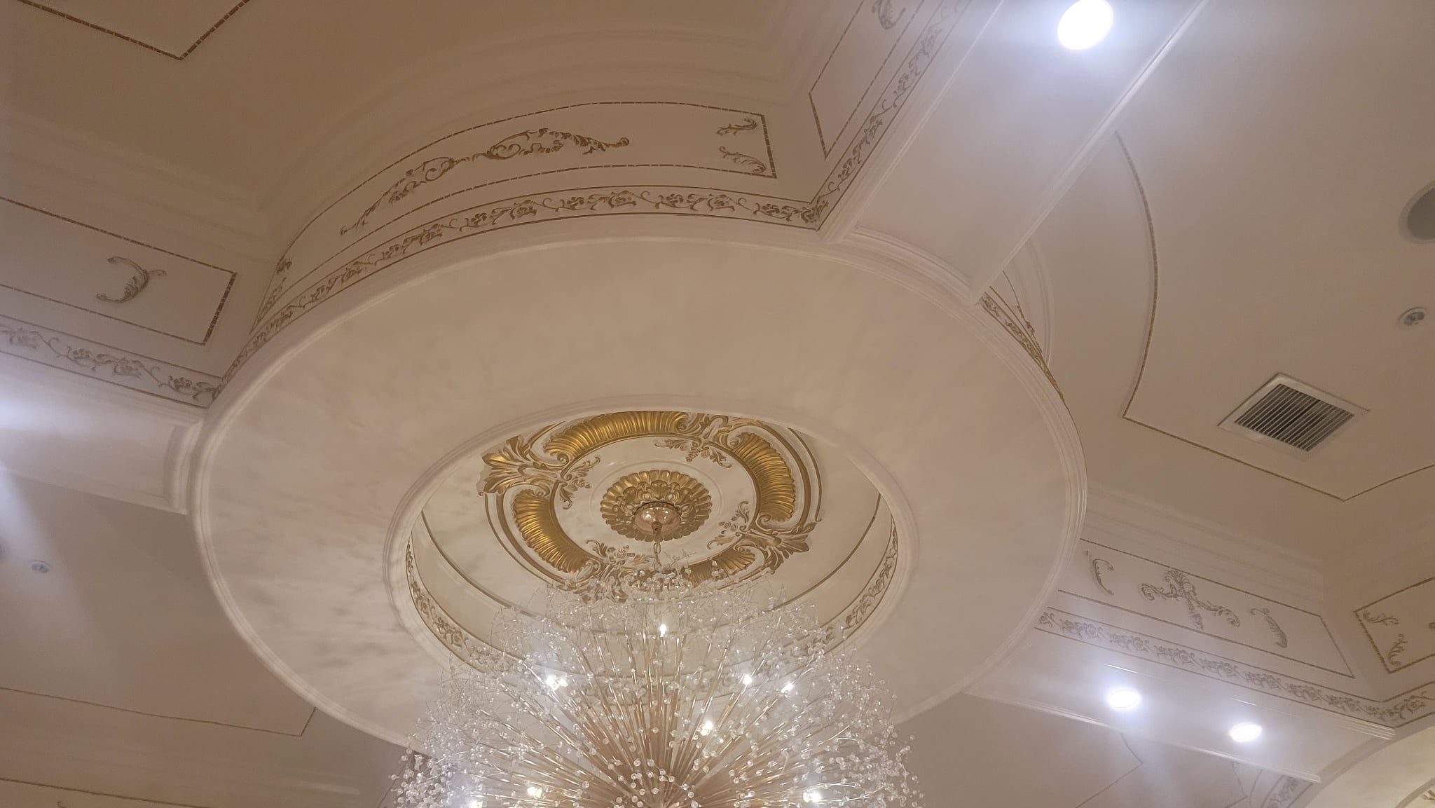 Chandelier hanging from a decorated ceiling