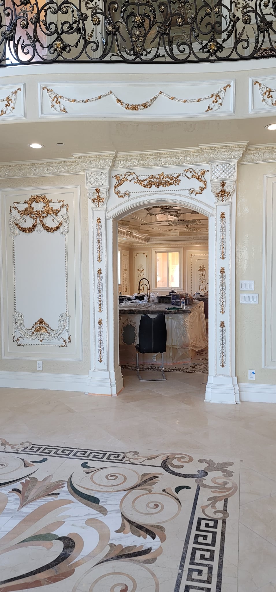 Decorative interior with ornate wall moldings and marble floor.